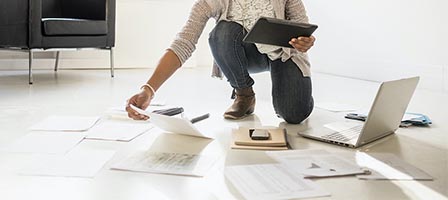 Person organizing papers and using tablet