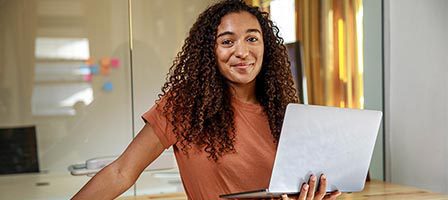 Confident woman holding laptop indoors