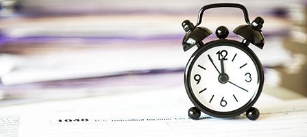 Black clock on paperwork stack