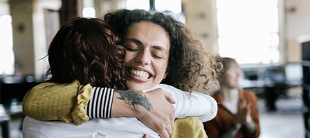 Friends embracing with big smiles.