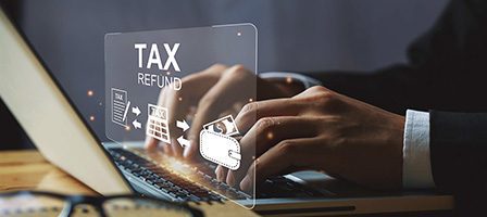 Hands typing on laptop, tax refund concept