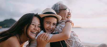 Three people smiling by the seaside