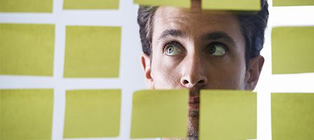 Man looking at sticky notes on glass