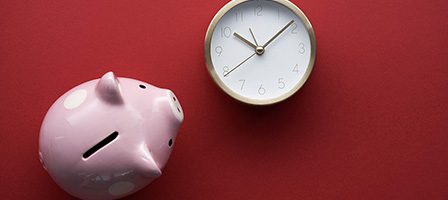 Piggy bank and clock on red background.