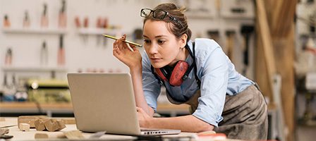 Woman working on laptop in workshop