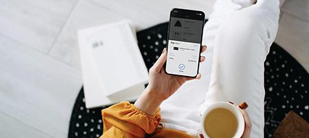 Person holding smartphone and coffee