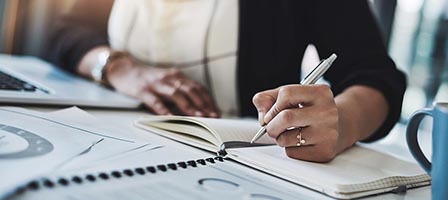 Hand holding pen over notebook
