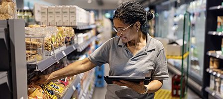 Store employee organizing shelves with tablet