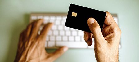 Hand holding credit card near keyboard