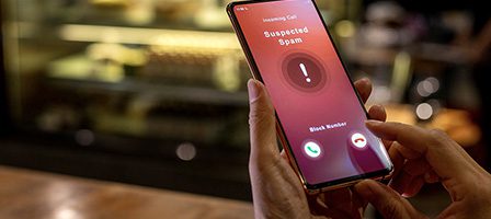 Person holding phone with spam warning