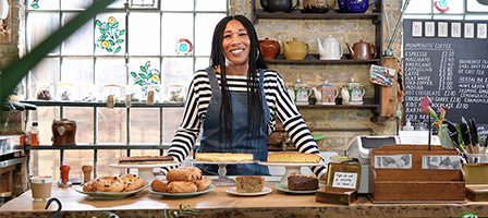 Café owner displaying pastries and cakes