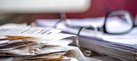 Stack of papers and eyeglasses on desk