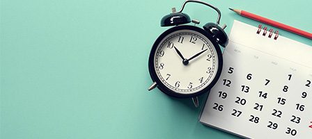 Alarm clock beside monthly calendar