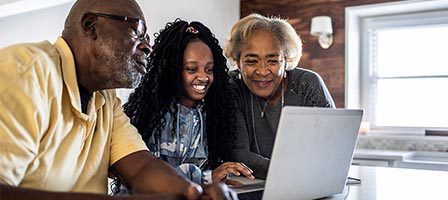 Elderly couple and young woman using laptop