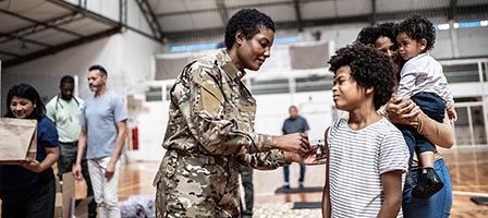 Soldier interacting with a family indoors.