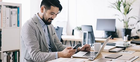 Office worker using smartphone and laptop