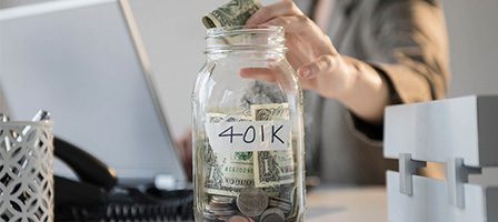 Hand placing cash in savings jar