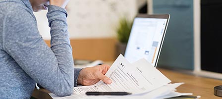 Person reviewing documents in front of laptop