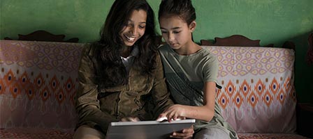 Smiling duo sharing a laptop moment