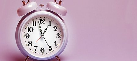 Classic alarm clock on pink surface