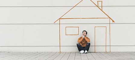 Man seated beside house outline mural