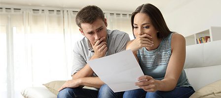 Concerned couple reviewing paperwork at home