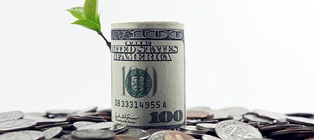 Rolled dollar bill among scattered coins