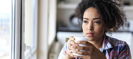 Woman gazing out window with coffee