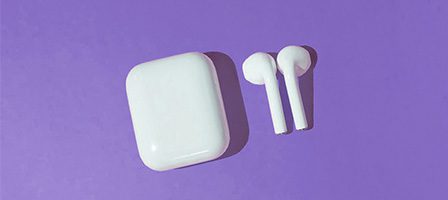 Earbuds and case set on violet surface