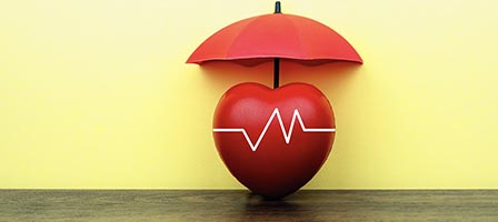Red umbrella over heart on wooden surface