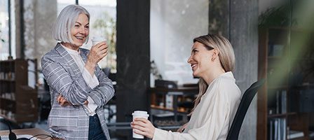 Two women smiling during office conversation