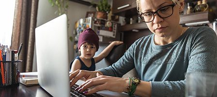 Mother multitasking with computer and child