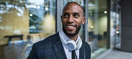 Man with headphones smiling outside office building