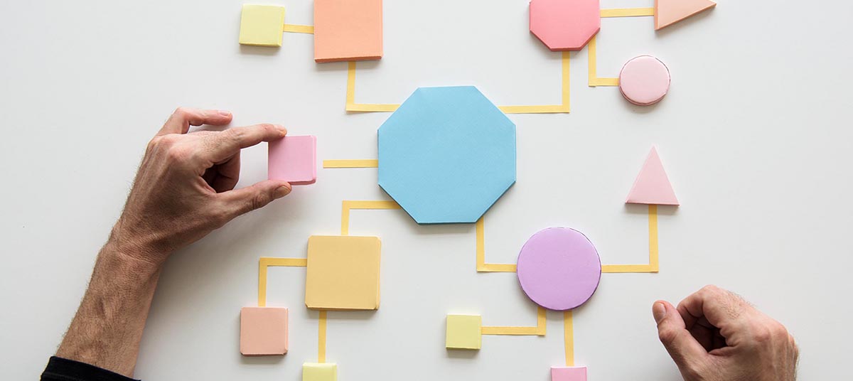 Person organizing pastel shapes into a diagram.