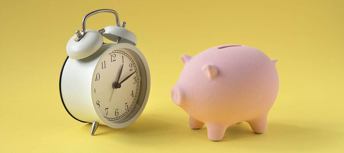 Vintage clock beside a pink piggy bank.