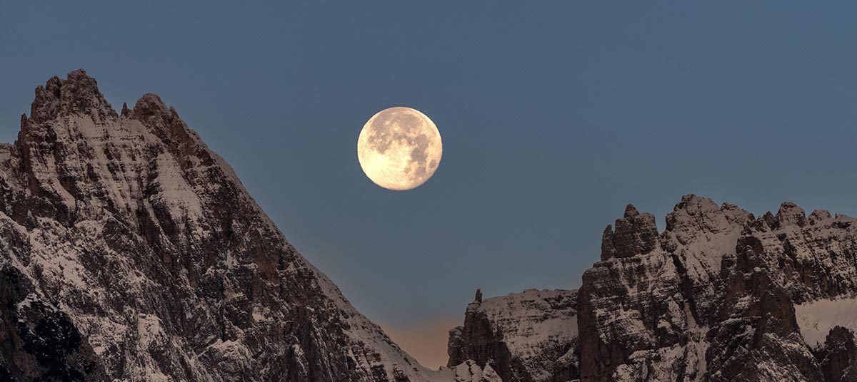 Moonrise above rugged mountain landscape