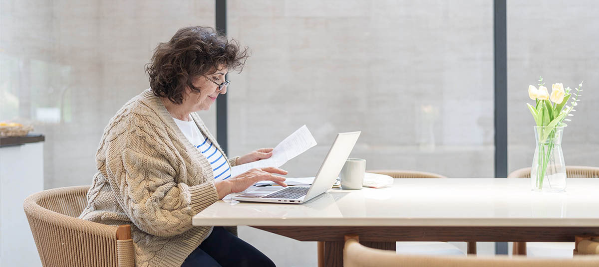 Senior reading documents with laptop