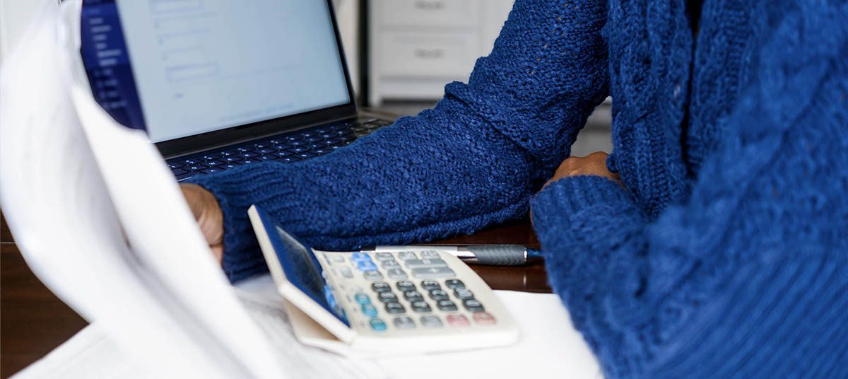 Blue sweater, laptop, and calculator on desk
