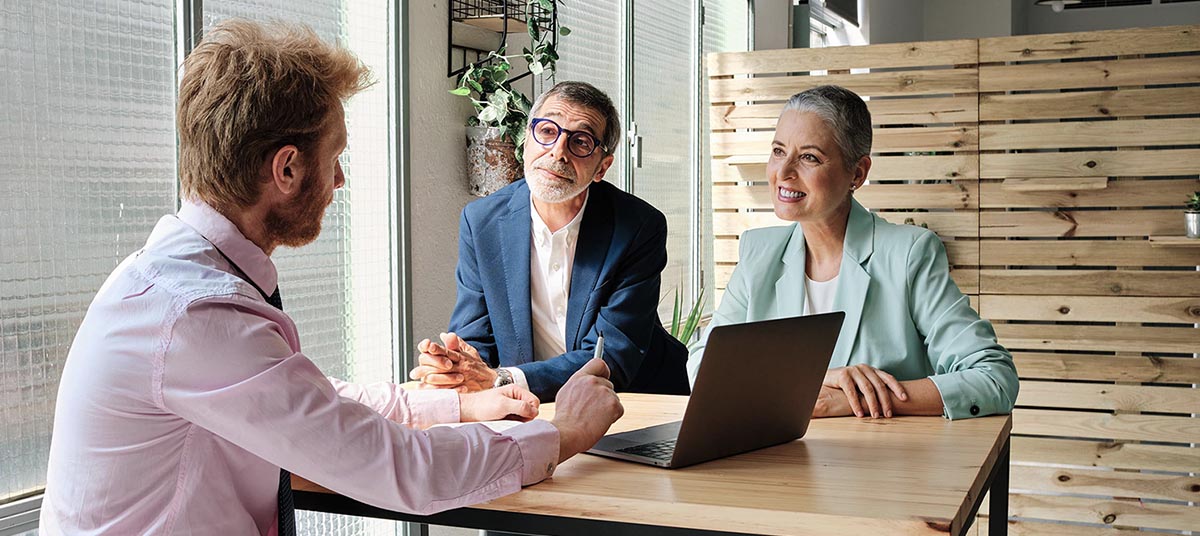 Business meeting with three people at table.