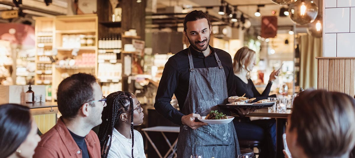 Waiter serving food to customers in restaurant