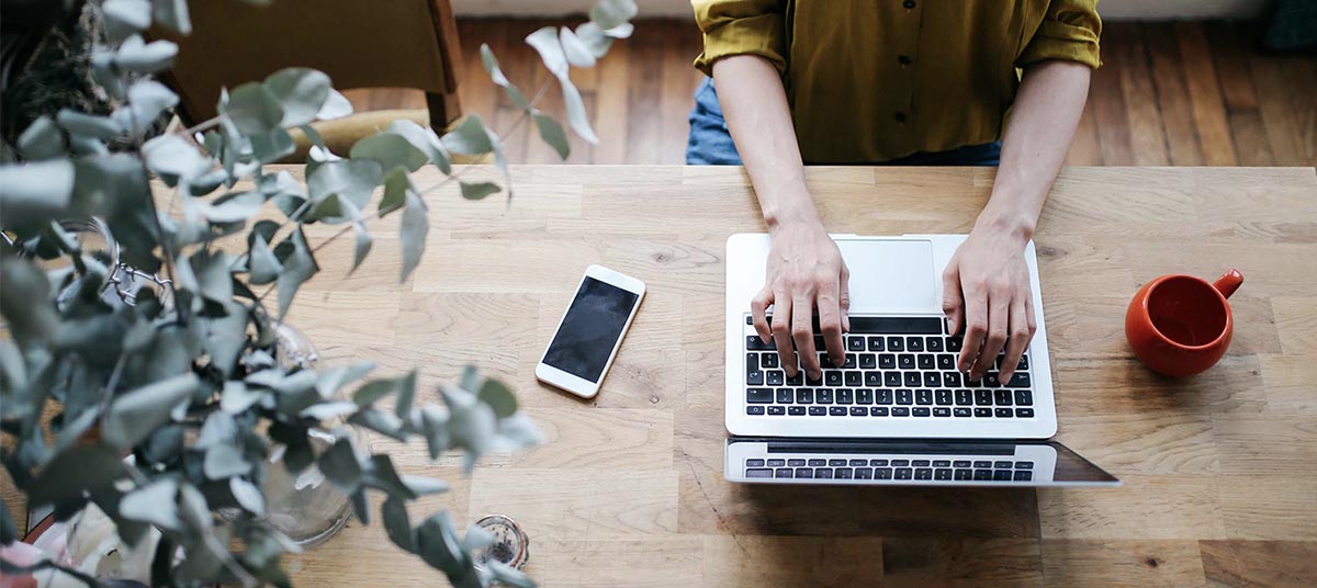 Typing on laptop at wooden desk