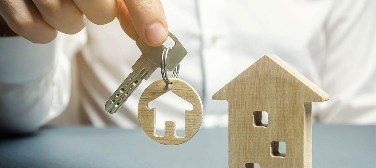 Person presenting house key and wooden model