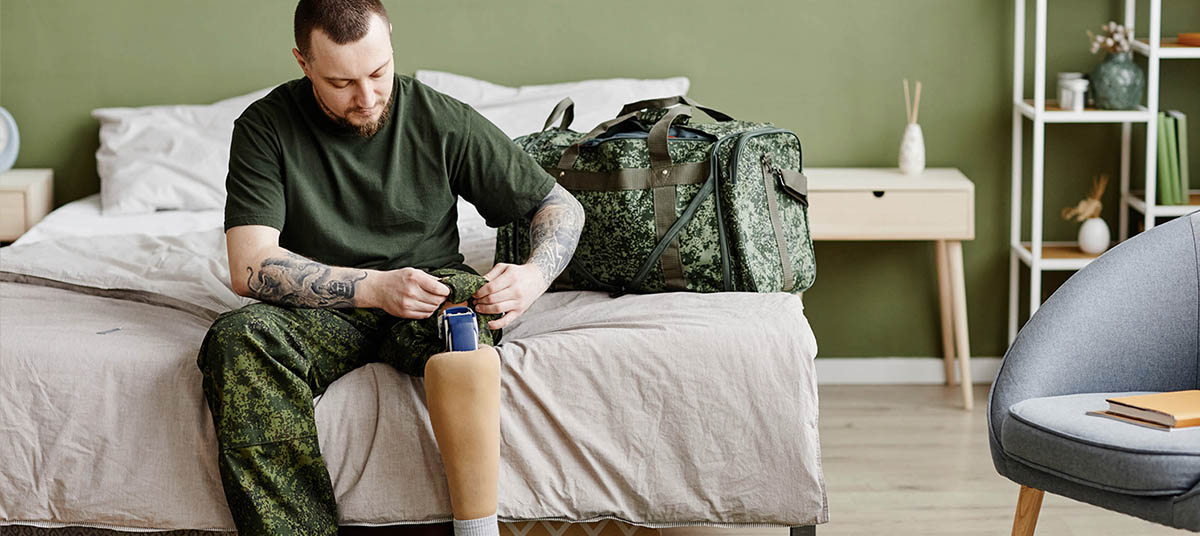 Man adjusting prosthetic leg on bed