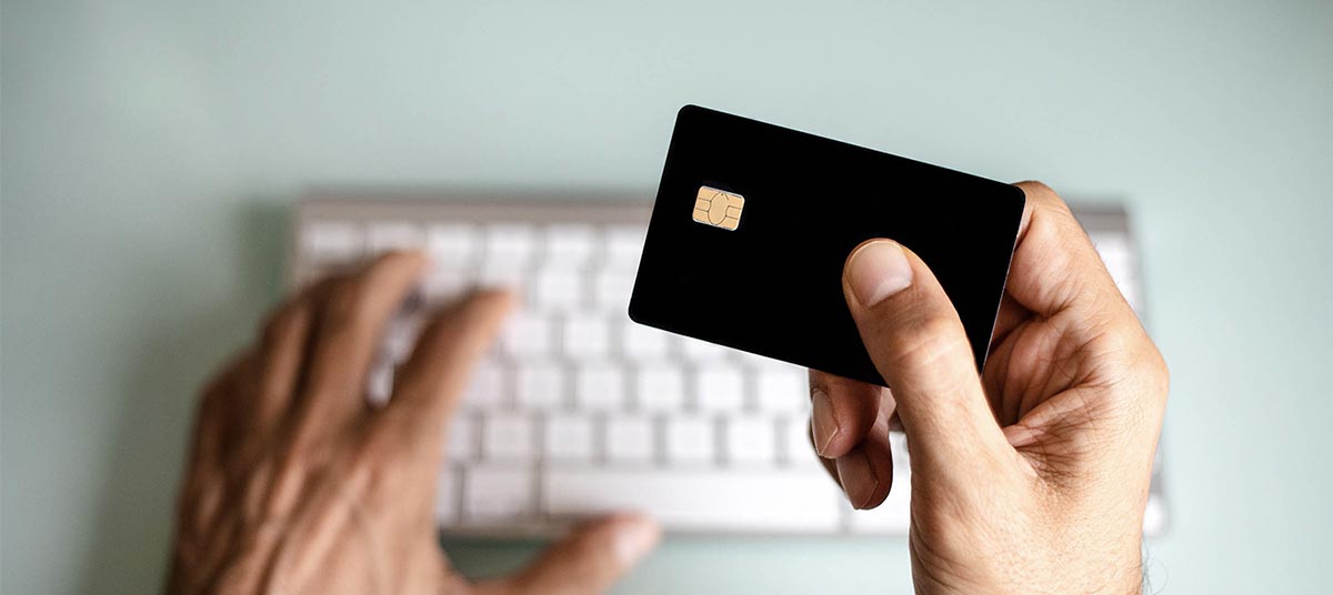 Person holding credit card near keyboard