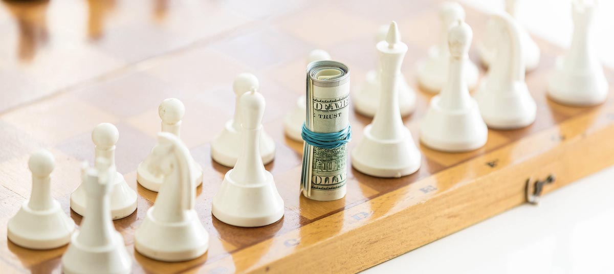 Chess pieces with rolled dollar bills