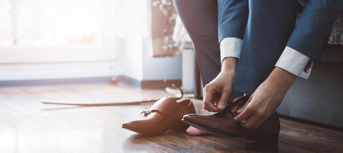 Hands adjusting brown leather shoes