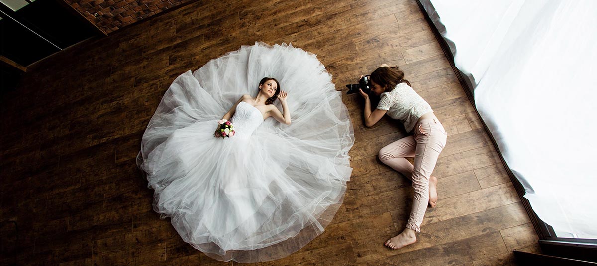 Photographer taking picture of bride on floor.
