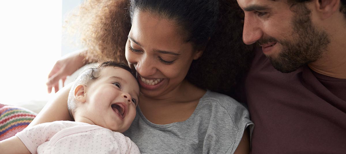 Parents cuddling joyful baby