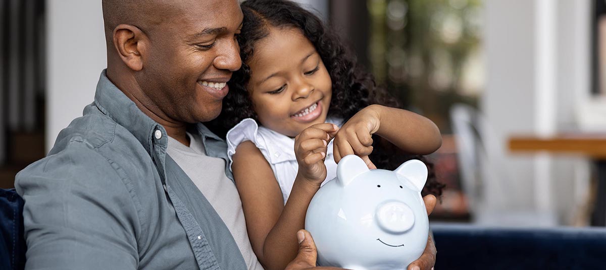 Child inserting coin into piggy bank