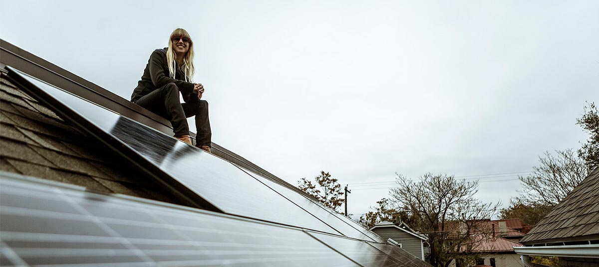 Person sitting on rooftop solar panels